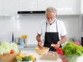 An elderly Caucasian man wearing an apron The symptoms to eat consist of various types of accommodation Alone in the kitchen Royalty Free Stock Photo