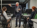 Elderly Caucasian man wearing a clown nose swears at his subordinates. Royalty Free Stock Photo