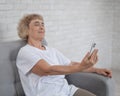 An elderly Caucasian woman suffers from farsightedness and tries to read a message on a smartphone with her arm