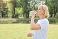 Elderly caucasian woman wearing white shirt holding and drinking water bottle. refreshing during the holidays Royalty Free Stock Photo