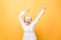 Elderly cheerful woman with headphones listening to music on a phone and dancing isolated on yellow background Royalty Free Stock Photo