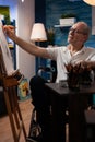 Elderly citizen drawing still nature on easel in home art studio for hobby and recreation