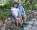 Elderly couple in an affectionate pose sitting on a stone wall in a garden in Colorado. Royalty Free Stock Photo
