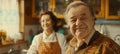 Elderly couple in aprons prepare colorful salad together, husband in orange jacket smiles cheerfully