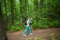 Elderly couple with backpack hiking in forest.