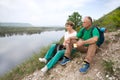 Elderly couple with backpacks travels around mountains.