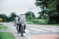 An elderly couple carefully cycled together on the highway, with their husband taking care of them behind them.Concepts about Royalty Free Stock Photo