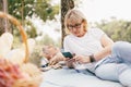 Elderly couple of caucasian using smartphone together in the park, Senior couple relax in summer daylight. relaxing concept of lif