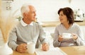elderly couple drinking coffee in the kitchen while sitting at the table. Royalty Free Stock Photo