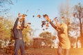 Elderly couple happily throws autumn fall leaves sitting in a park. Positive emotions of the elderly