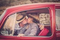 Elderly couple with hat, with glasses, with gray and white hair, with casual shirt, on vintage red car on vacation enjoying time Royalty Free Stock Photo