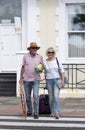 Senior holidaymakers with a suitcase and deckchair