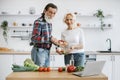 Elderly couple husband and wife spend free time together in kitchen making healthy salad.