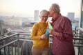 An elderly couple in love is having romantic moments while enjoying a drink on the terrace of an apartment at a beautiful sunset Royalty Free Stock Photo