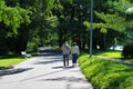 An elderly couple - a man and a woman, walk close to each other along the empty Yelagin alley of the St. Petersburg park