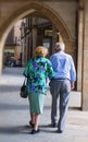 An elderly couple of pensioners strolling down the city street.