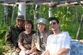 An elderly couple of rural Asian Yakuts and a young girl with a Russian family man pose on a bench at a table in an open-air fores