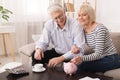 Elderly couple saving money in piggybank at home Royalty Free Stock Photo