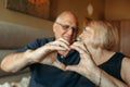 An elderly couple shows a heart with their hands as a sign of love, look at each other Royalty Free Stock Photo