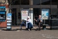 Elderly couple sit on a bench beside Jehovahs Witness stand talking and discussing