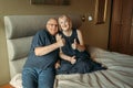 An elderly couple sits on a bed and shows a gesture with their hands - thumbs up, like