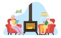 Elderly couple sitting in armchair. Grandparents reading books. People relaxing in front of fireplace. Cozy home leisure Royalty Free Stock Photo