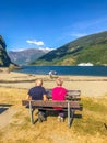 Elderly couple sitting on the bench and enjoying the view on a fjord