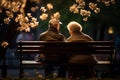 Elderly couple sitting on a bench in park, flowers all around, loneliness Royalty Free Stock Photo