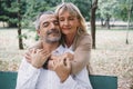 Elderly couple sitting on a bench showing love by hugging together at the garden in the morning Royalty Free Stock Photo