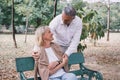 Elderly couple sitting on a bench showing love by hugging together at the public park in the morning. Happy concept of lifestyle Royalty Free Stock Photo