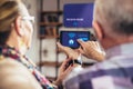 Elderly couple sitting comfortably on a sofa with their backs holiding remote control home system Royalty Free Stock Photo