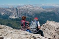 Elderly Couple Sitting on Stones in Front of Mountains Panorama