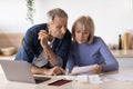 Elderly couple sitting at table using laptop, paying bills Royalty Free Stock Photo