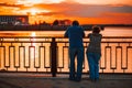 Elderly couple standing back on the river bank and watching the sunset