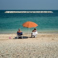 Elderly couple sunbathes sitting at seaside Royalty Free Stock Photo