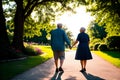 An elderly couple walking down a path holding hands.