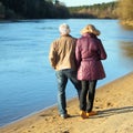 Elderly couple walking hand in hand along the shore. View from the back Royalty Free Stock Photo