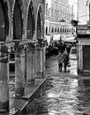 An elderly couple walking on the wet streets of Venice near Rialto Bridge and arcades of the fish market. Italy