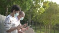 Elderly couple wearing face mask surfing phones at the park Royalty Free Stock Photo