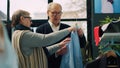 Elderly customers analyzing elegant shirts on hangers at retail store, Royalty Free Stock Photo