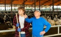 Elderly dairy farm owner tells young helper what to do