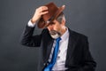 Elderly dandy man in suit with tie takes off his hat for a greeting