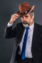 Elderly dandy man in suit with tie takes off his hat for a greeting