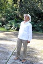 Elderly dark-skinned Latino man in his 60s relaxed in his retirement dressed in a guayabera, hat and sunglasses walks in the park