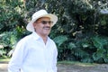 Elderly dark-skinned Latino man in his 60s relaxed in his retirement dressed in a guayabera, hat and sunglasses walks in the park