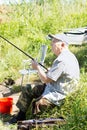 Elderly disabled man fishing on a river bank Royalty Free Stock Photo