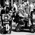 Elderly Disabled Man Sitting On Electric Mobility Scooter Next To A Young Child