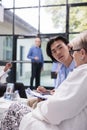 Elderly doctor explaining medication treatment to asian man during checkup visit consultation in hospital Royalty Free Stock Photo