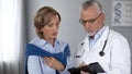 Elderly doctor explaining test results to shocked lady, expensive medicine Royalty Free Stock Photo