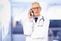 Elderly doctor talking with his patient on his mobile phone while standing in hospital Royalty Free Stock Photo